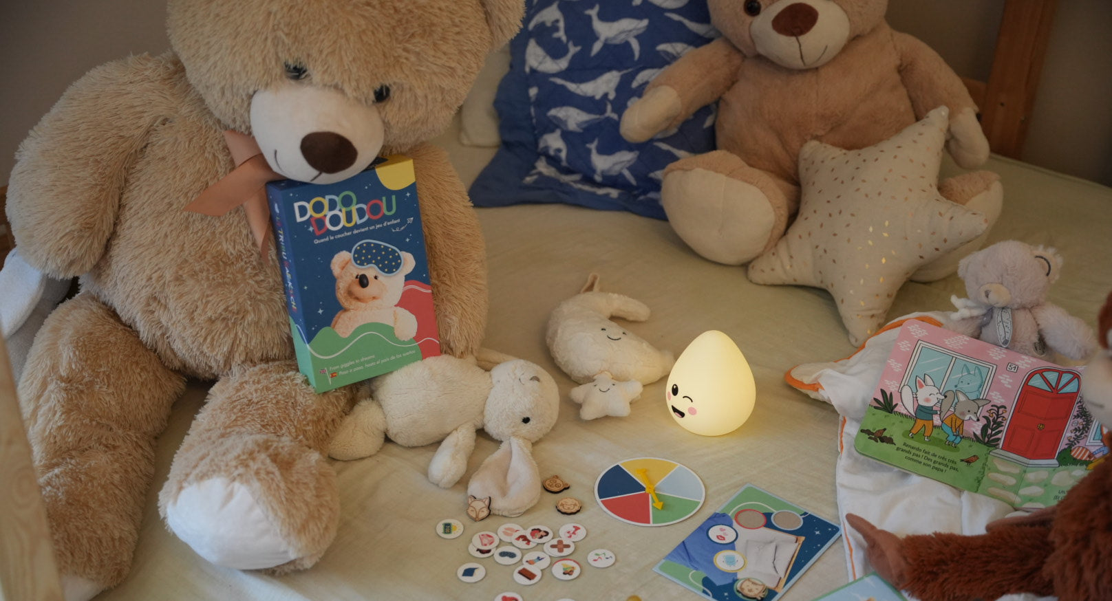 une boite de jeu dodo doudou ouverte dans un lit d'enfant simulant une partie de jeu